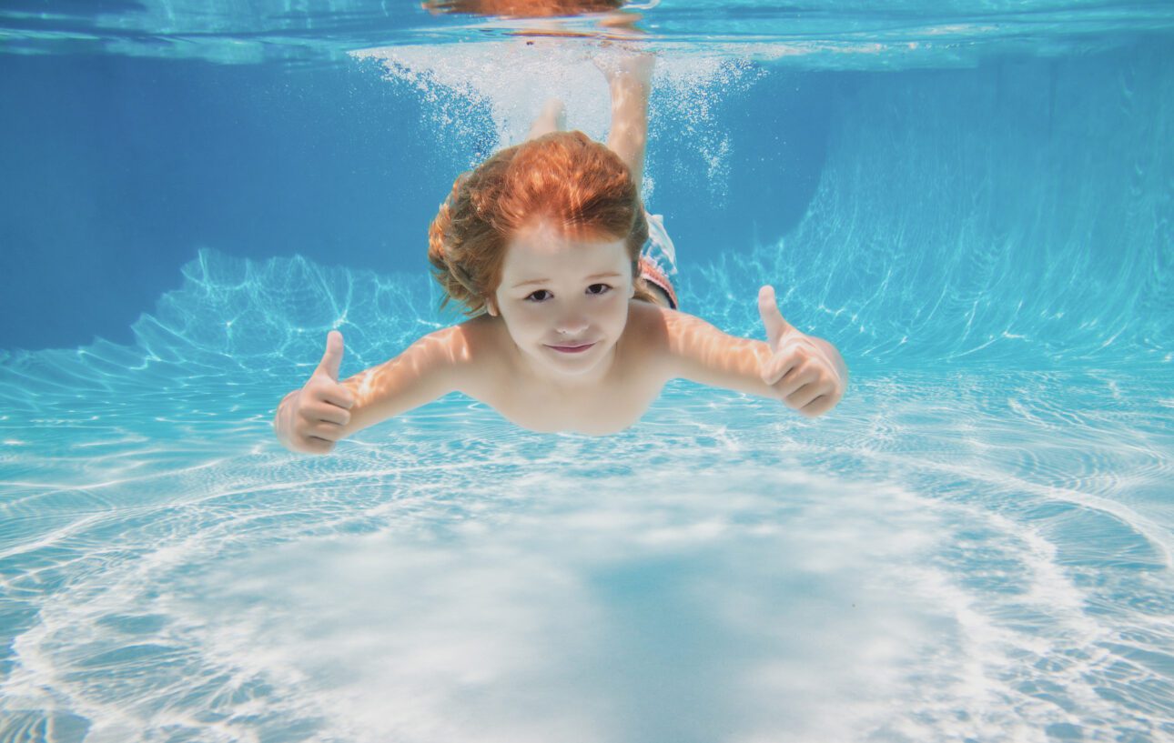 Kind beim schwimmen unter Wasser mit Daumen nach oben